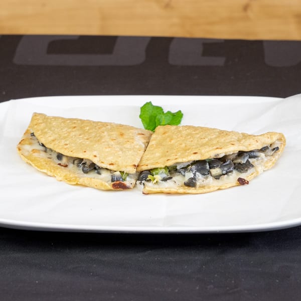 Two quesadilla halves filled with black beans and cheese, garnished with mint on a white plate.