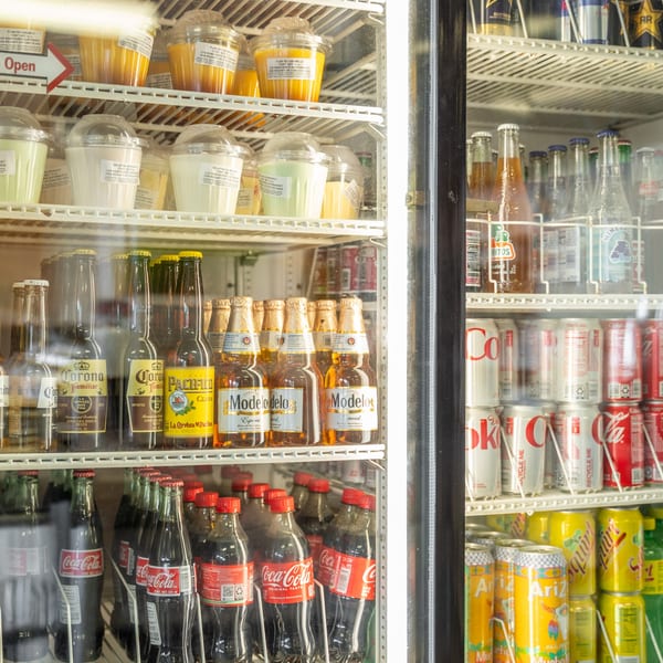 A refrigerated display case filled with various Mexican desserts, beers, and sodas.
