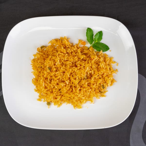 A white rectangular plate filled with golden yellow rice and garnished with a sprig of mint.