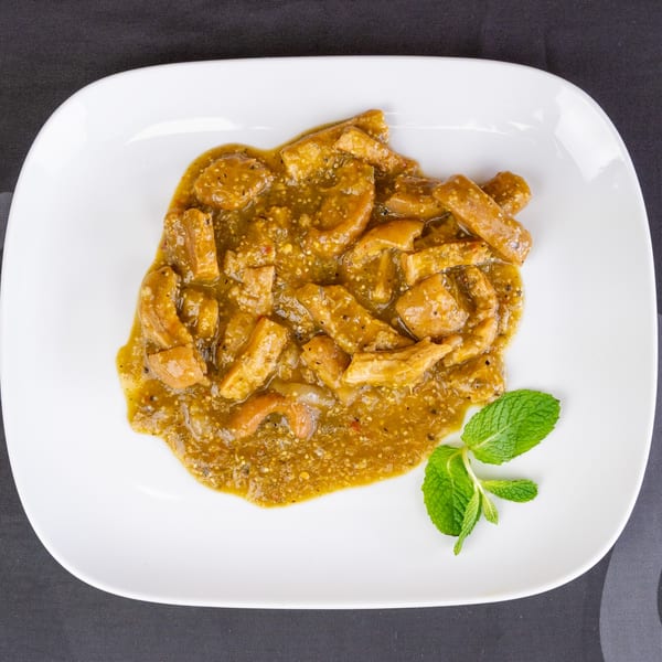 Overhead view of a white plate filled with green chili stew and a sprig of mint.