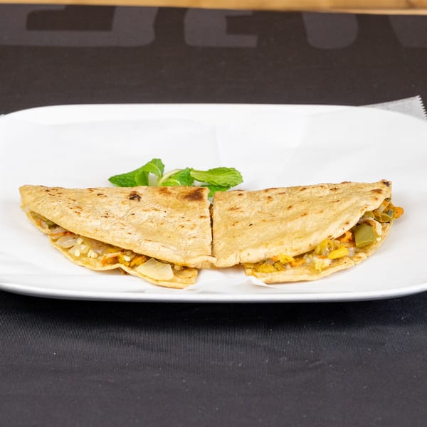 Two halves of a quesadilla filled with vegetables and cheese, garnished with mint leaves.