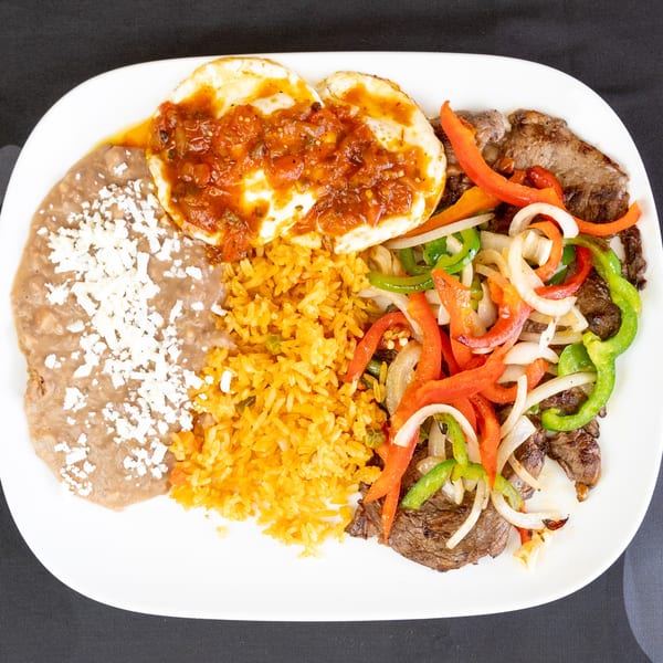 A white plate with steak fajitas, refried beans, rice, and two fried eggs with salsa.